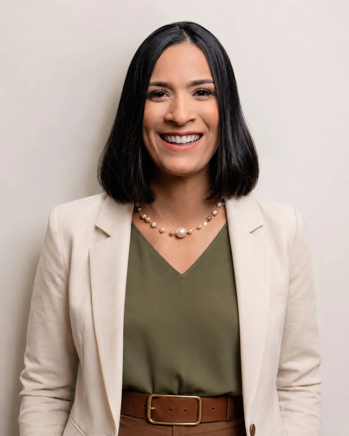 Jéssica Guimarães, psicóloga, sorrindo, de blazer claro e blusa verde